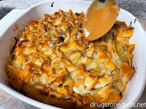 Baked Cookie Butter Baklava in a pan getting cookie butter drizzled on top with a spoon.