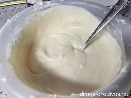 Cream cheese fruit dip in a clear bowl with a spoon in it.