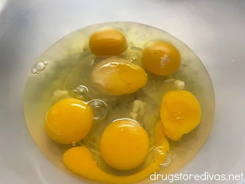 Six eggs cracked in a clear bowl.