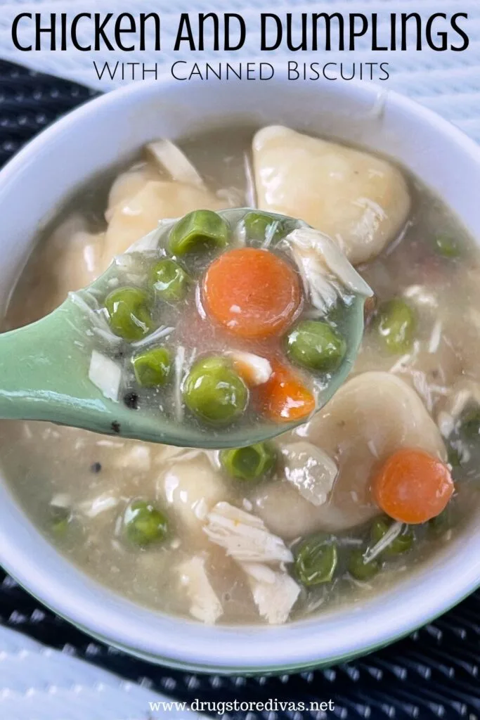 A green spoon filled with peas, carrots, and chicken pieces above a bowl of chicken and dumplings in a green bowl on a white and black tablecloth with the words "Chicken And Dumplings With Canned Biscuits" digitally written on top.