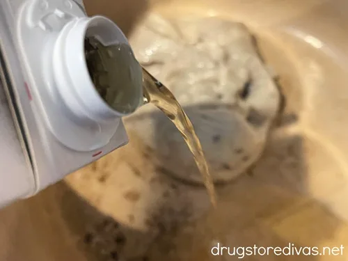 Chicken broth being poured into a Dutch oven that already has cream of mushroom soup in it.