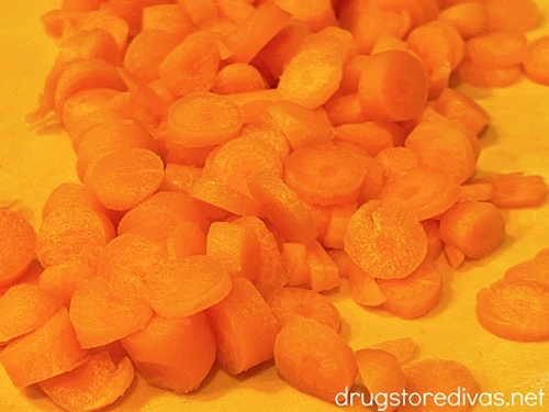 Chopped carrots on an orange cutting board.