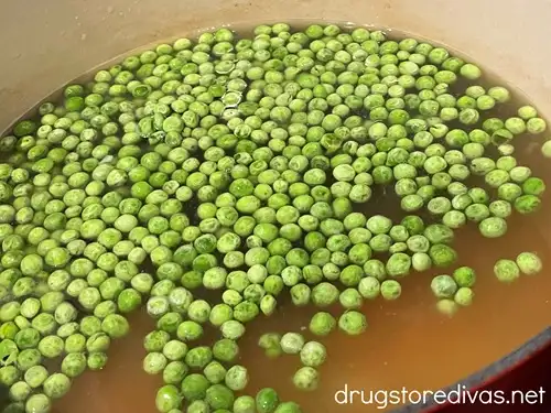 Peas floating on top of soup in a Dutch oven.