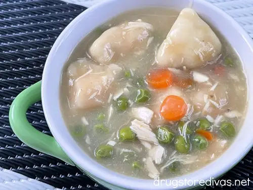A green and white bowl filled with chicken and biscuits.