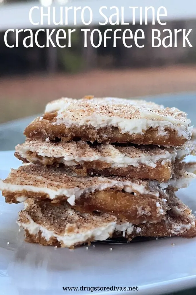 Four pieces of white chocolate topped toffee crackers stacked on a white plate with the words "Churro Saltine Cracker Toffee Bark" digitally written on top.