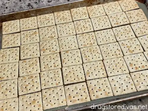 Saltine crackers lined on a baking tray.