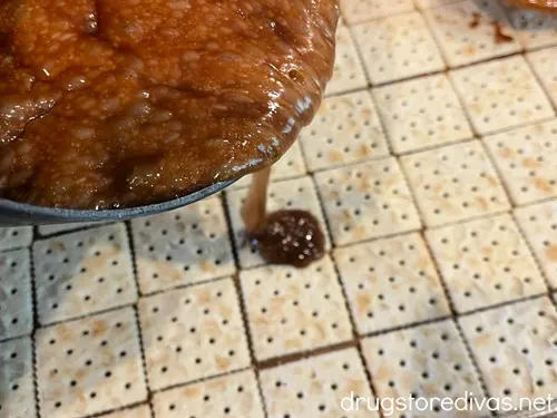A caramel being poured on top of saltine crackers.