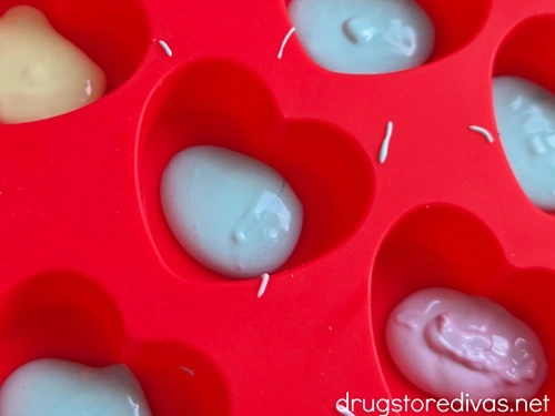Colored melted chocolate in the bottom of cavities of a heart-shaped mold.
