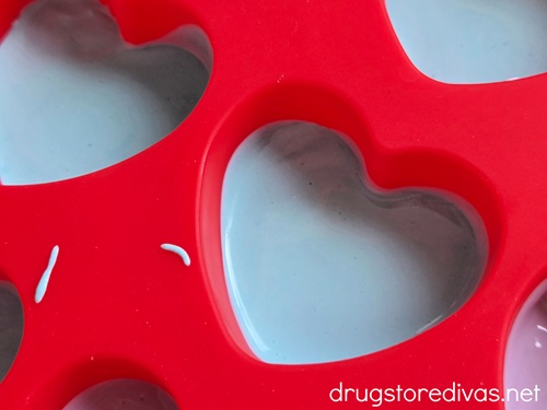 Colored melted chocolate in the bottom of cavities of a heart-shaped mold.
