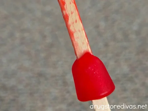 A red Dot candy on a lollipop stick.