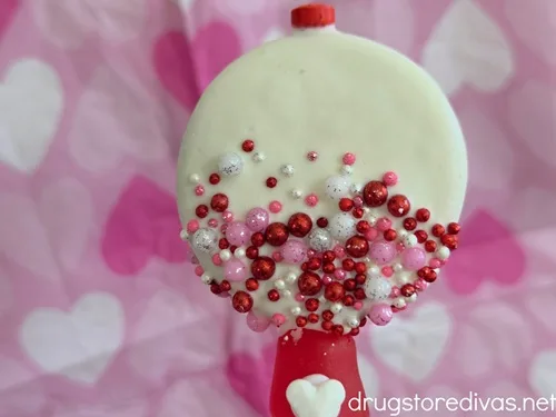 An Oreo cookie decorated to look like a gumball machine on a heart-patterned napkin.