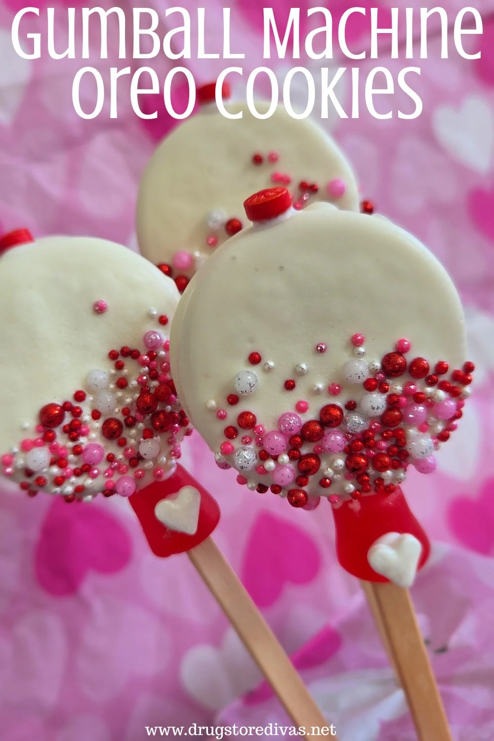 Three Oreo cookies, decorated to look like gumball machines, on sticks with a heart-patterned napkin behind them and the words 