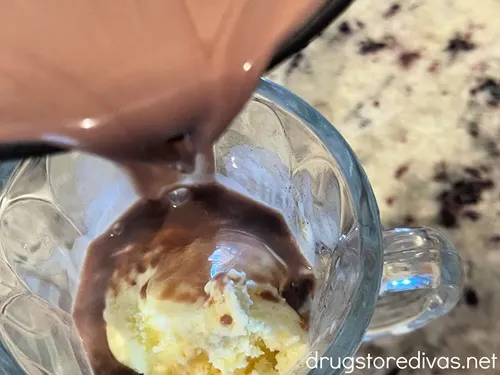 Hot chocolate being poured on top of white gelato in an Irish coffee glass.