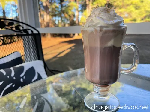 A hot chocolate affogato with whipped cream in an Irish coffee glass on a table.