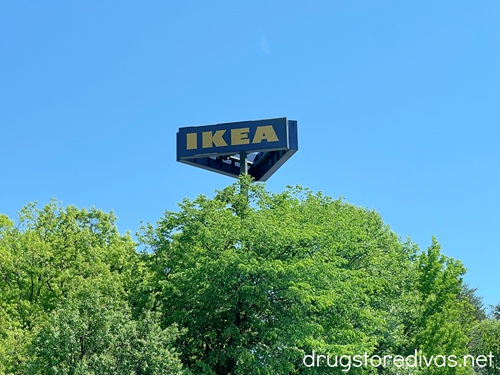 A blue sign that says IKEA above trees.