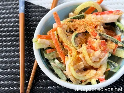 A pair of chopsticks next to spicy kani salad in a bowl.