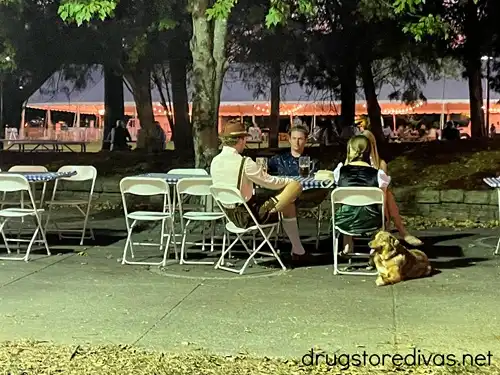 Three people at a table with folding chairs at Nashville Oktoberfest.