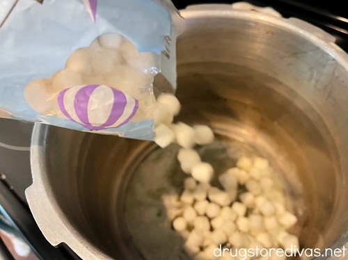 Mini marshmallows being poured into a large silver stockpot.
