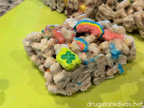 A Lucky Charms marshmallow treat on a green cutting board.