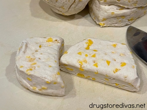 A canned biscuit cut in half on a white cutting board.