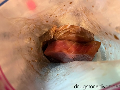 Two tuna steaks in a bag with a dark marinade.