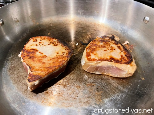 Two cooked tuna steaks in a silver pan.