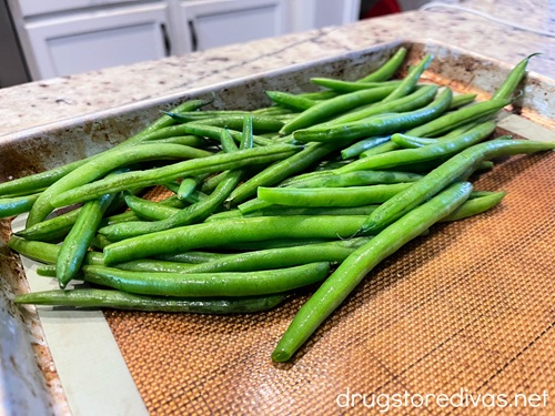 Fresh green beans on one side of a sheet pan.