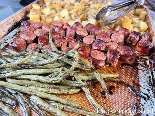 Cooked sheet pan sausage and potatoes with green beans.