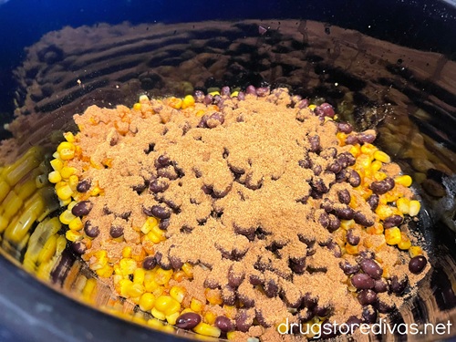 Corn kernels, black beans, and taco seasoning in a slow cooker.