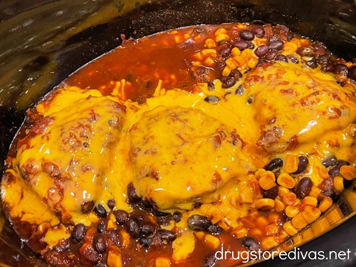 Melted cheese on top of cooked corn and beans in a slow cooker.