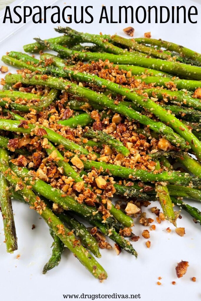 Asparagus with chopped almonds on top on a white tray with the words "Asparagus Almondine" digitally written on top.