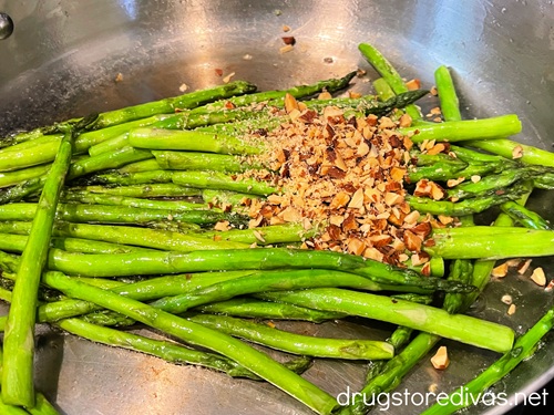Asparagus with chopped almonds on top in a silver skillet.