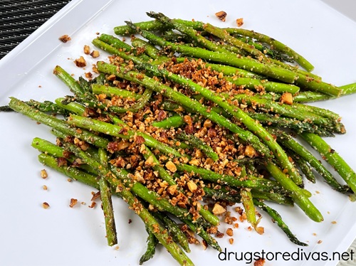 Asparagus almondine (asparagus topped with chopped almonds) on a white tray.