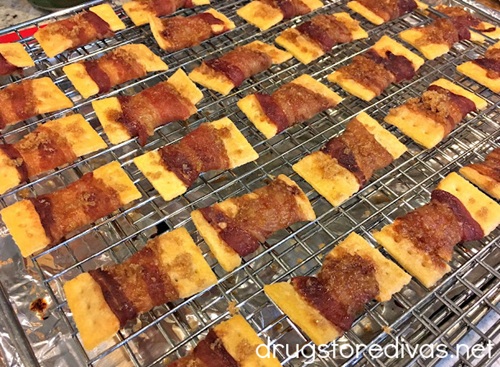 Club crackers wrapped in cooked bacon on a wire rack.
