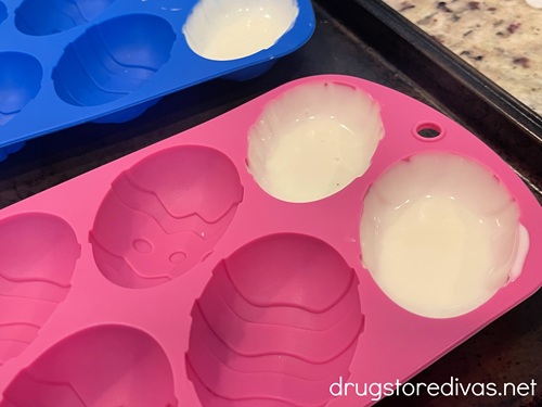 White chocolate in egg shaped cavities of a silicone mold.