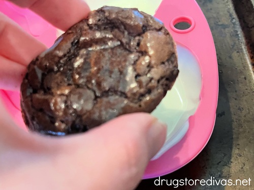A hand placing a brownie into a pink silicone mold.