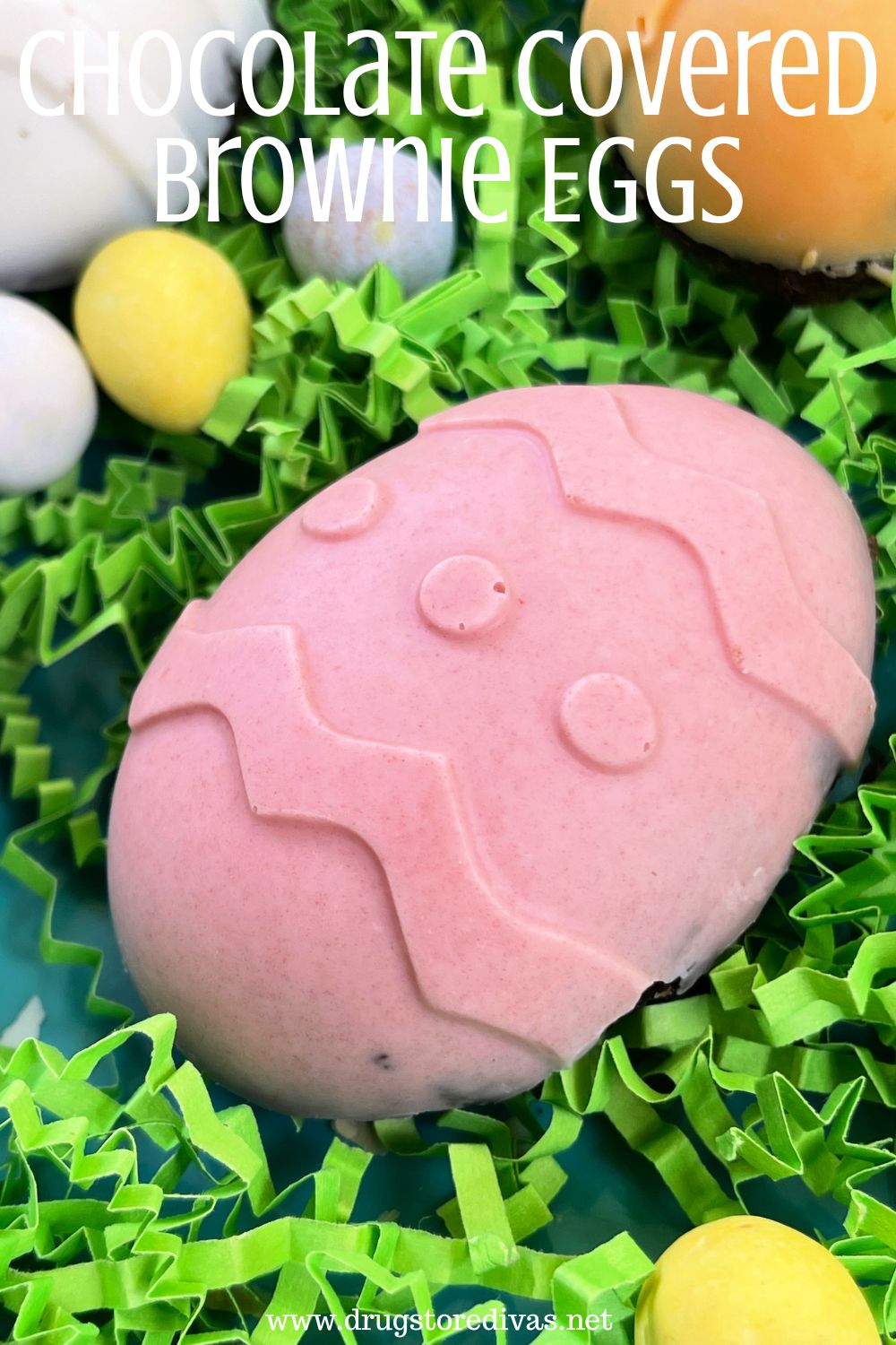 A pink chocolate covered Easter egg on green paper shred with mini eggs around it and the words 