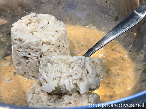 Crab meat in a metal bowl with dressing at the bottom.
