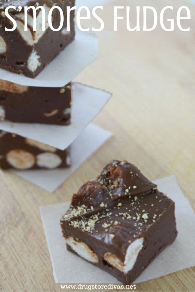 Three pieces of fudge with parchment between them stacked in the back an one with parchment in the front with the words "S'mores Fudge" digitally written on top.