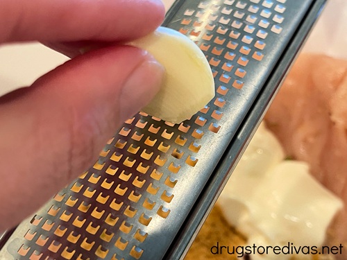 Garlic being grated above a bowl.