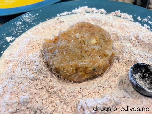 A chicken patty in seasoned breadcrumbs on a plate.