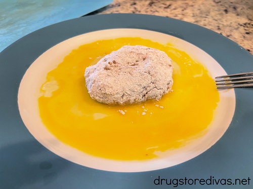 A chicken patty in a scrambled egg on a plate.