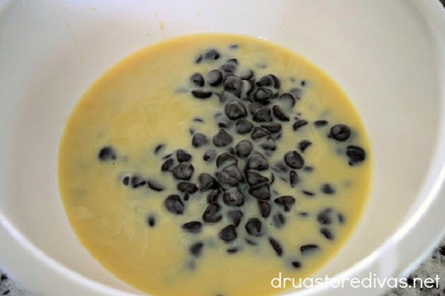 Chocolate chips and sweetened condensed milk in a white bowl.