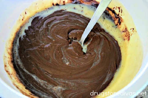 Melted chocolate in a white bowl with a spoon in it.