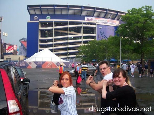 A man and two young women pretending to be baseball batters in front of Shea Stadium in New York.