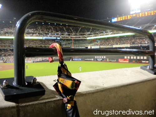 A baseball stadium at night, with an umbrella hanging on a railing.