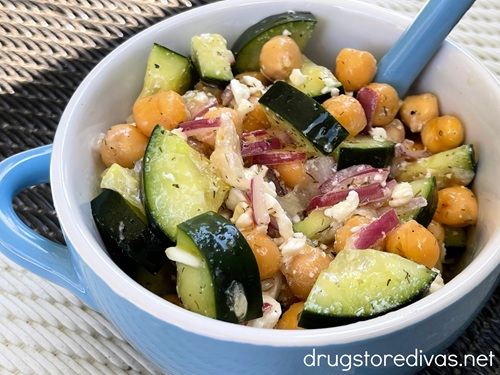 Cucumber chickpea salad in a blue bowl with a spoon in it.
