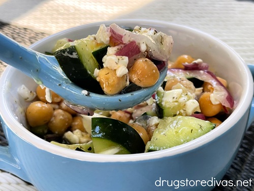 Cucumber chickpea salad in a blue bowl with a spoon holding some of the salad.