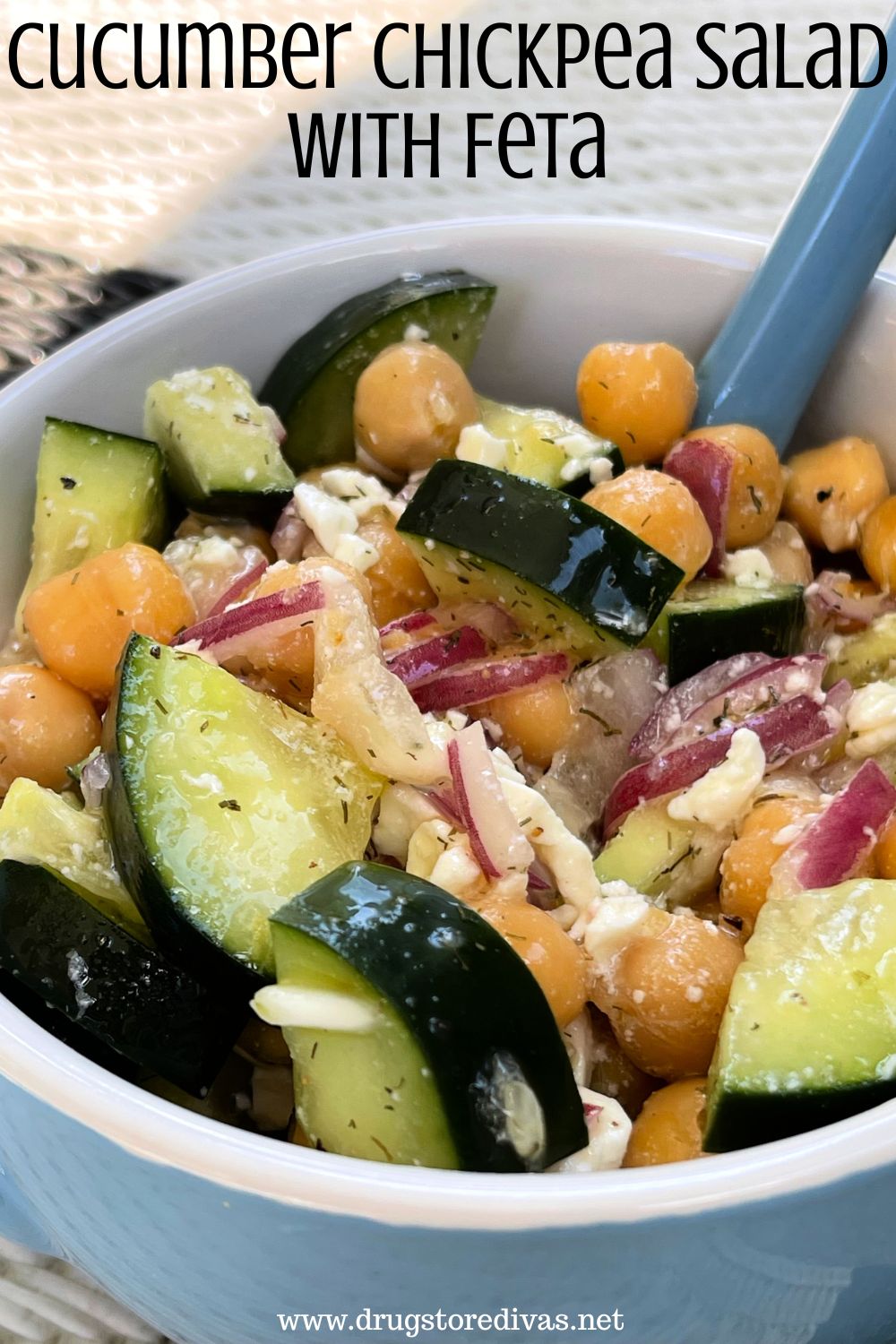 A blue bowl with a spoon in it filled with cucumber, red onion, and chickpeas with the words 
