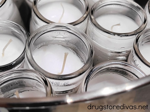 White candles in a silver bowl.